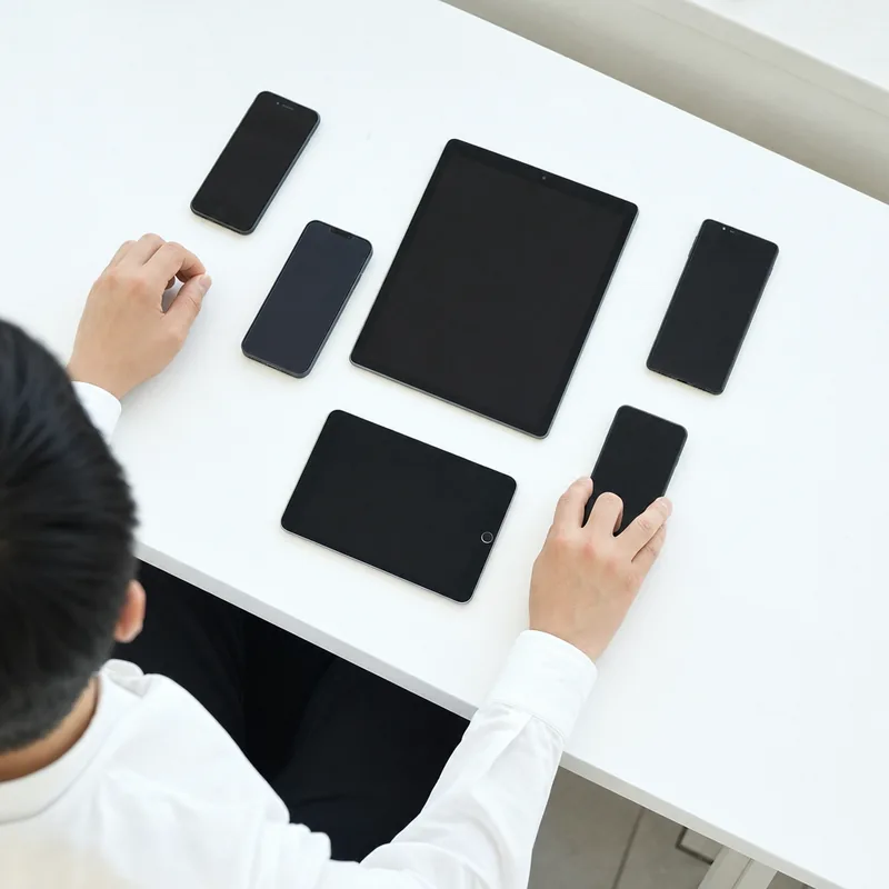 飲食店のバックオフィスのデスクに並ぶスマートフォンとタブレット